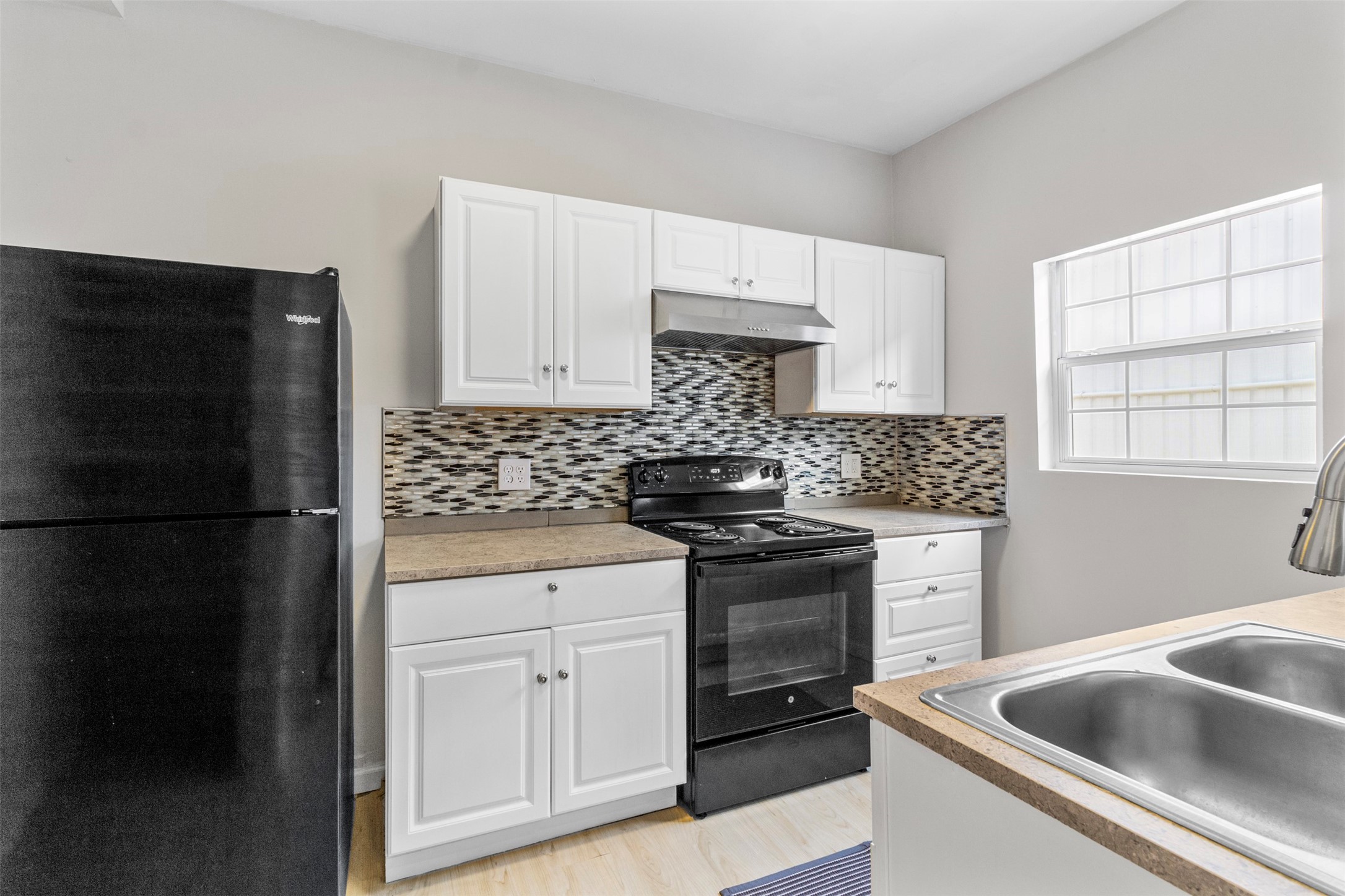 405 Medina Street, Unit B Houston, TX 77012 - Photo 6 of 16 a kitchen with white cabinets and black appliances