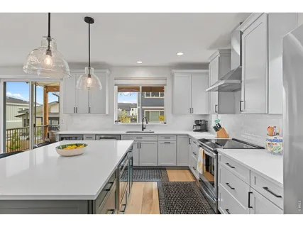 a kitchen with stainless steel appliances kitchen island a table chairs in it and white cabinets