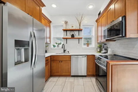 a kitchen with stainless steel appliances granite countertop a refrigerator a sink a stove and oven