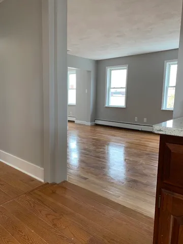 a view of an empty room with window and wooden floor