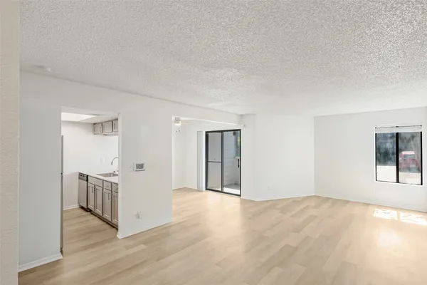 a view of an empty room with wooden floor and windows