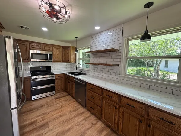 a kitchen with stainless steel appliances kitchen island a large counter top space a sink and a window