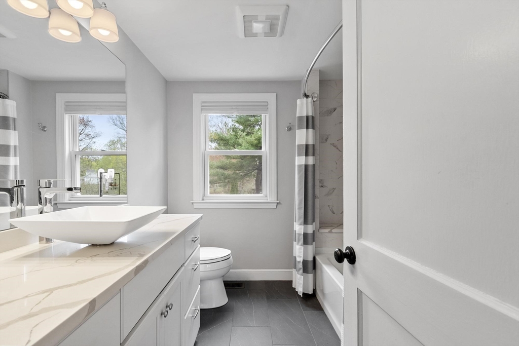 122 Southfield Road Concord, MA 01742 - Photo 13 of 28 a bathroom with a granite countertop sink a large mirror a bathtub and next to a window