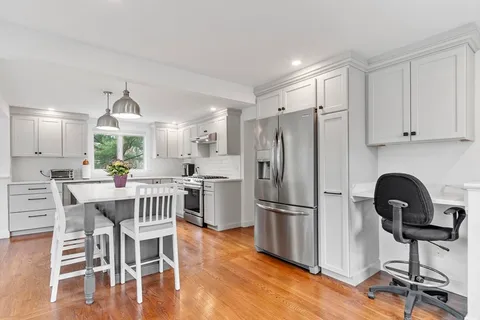 a kitchen with stainless steel appliances granite countertop a dining table chairs refrigerator and sink