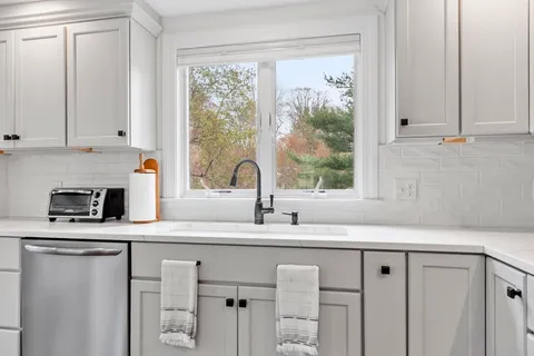 a kitchen with granite countertop a sink white cabinets and a window