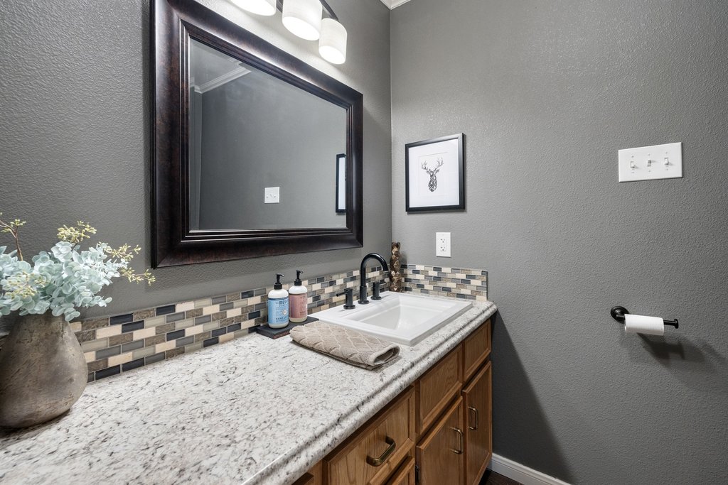 302 South Schramm Road Granger, TX 76530 - Photo 20 of 33 a bathroom with a granite countertop sink a mirror and a vanity