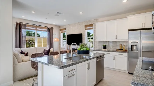 a kitchen with stainless steel appliances granite countertop a sink a stove and a refrigerator