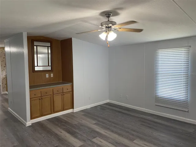 an empty room with wooden floor fan and windows