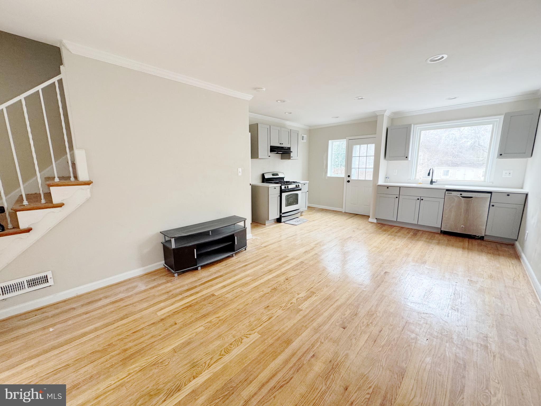 11969 Andrew Street Silver Spring, MD 20902 - Photo 3 of 20 a kitchen with stainless steel appliances wooden floors and white cabinets