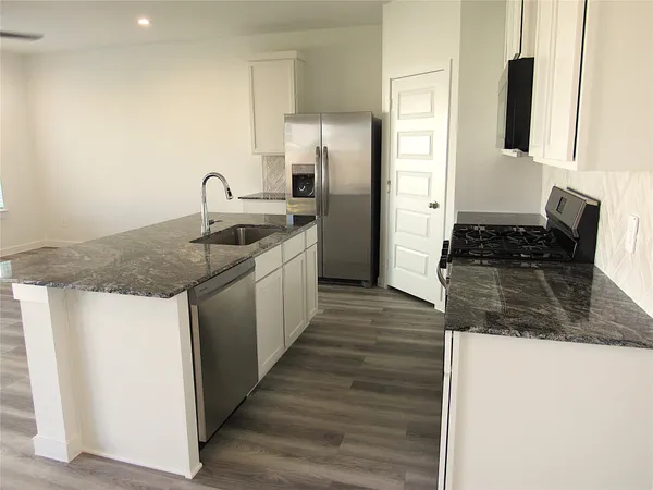a kitchen with stainless steel appliances granite countertop a sink stove and refrigerator
