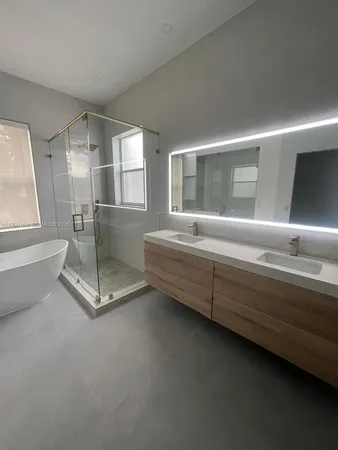 a large white kitchen with a sink and dishwasher a stove top oven with wooden floor