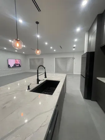 a large kitchen with a sink and dishwasher a stove top oven with wooden floor