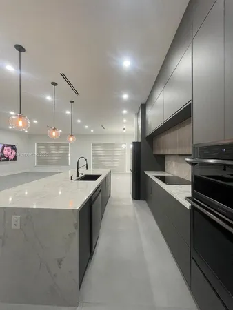 a kitchen with stainless steel appliances kitchen island granite countertop a refrigerator and a sink