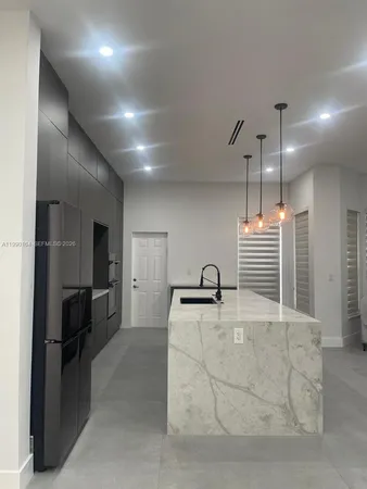 a large kitchen with kitchen island a large counter top a sink a stove and a refrigerator