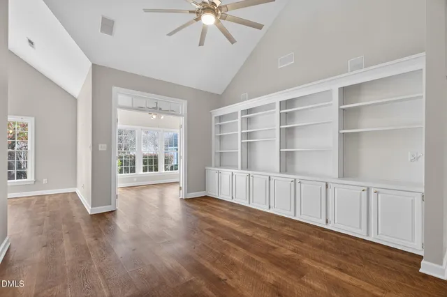 a view of an empty room with a window and wooden floor
