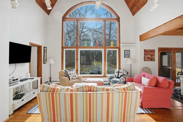 a living room with furniture a flat screen tv and a floor to ceiling window