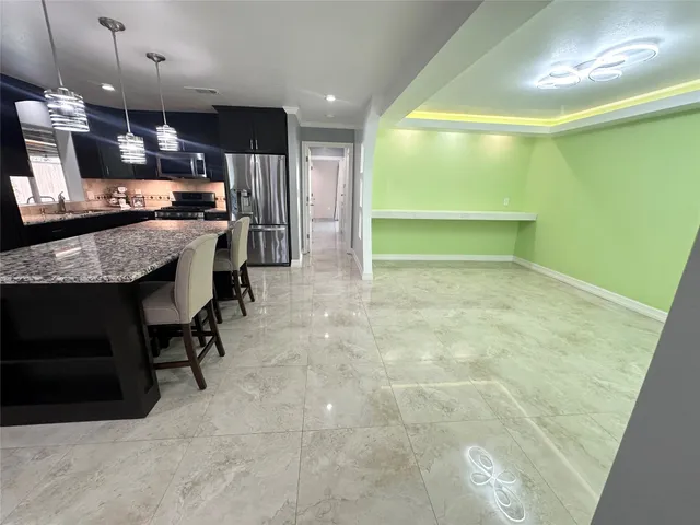 a living room with stainless steel appliances furniture a rug and a kitchen view