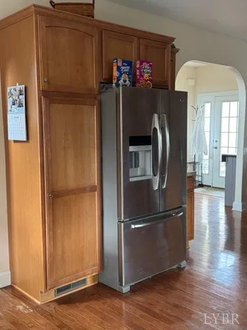a kitchen with refrigerator and wooden floor