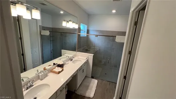 a bathroom with a sink a toilet a mirror and shower