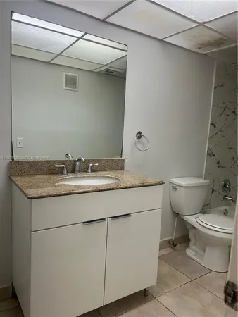 a bathroom with a granite countertop sink a toilet and a mirror