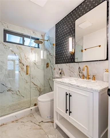 a bathroom with a granite countertop sink a toilet and shower