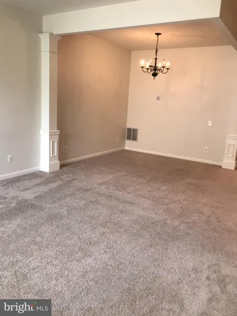 a view of an empty room with a chandelier fan