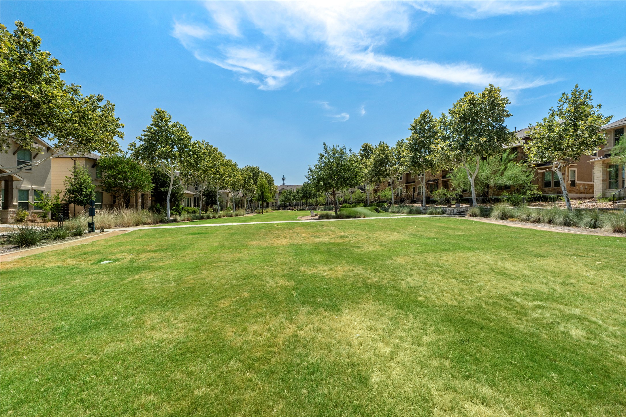 1709 Lawrence Street, Unit 5 Austin, TX 78741 - Photo 3 of 40 Mature trees and paved sidewalks frame a manicured neighborhood common green under sunny skies.