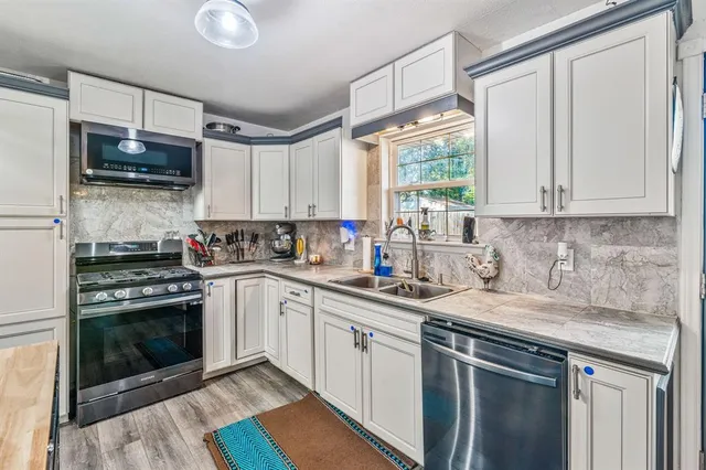 a kitchen with stainless steel appliances granite countertop a sink a stove and a microwave