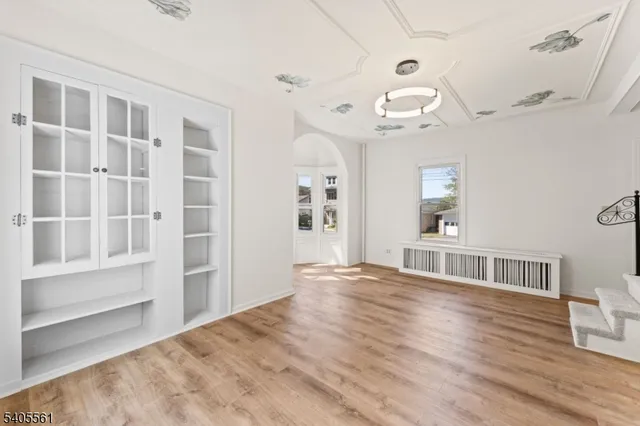 a view of an empty room with window and wooden floor