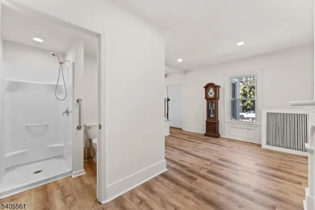 a view of an empty room with wooden floor and a bathroom