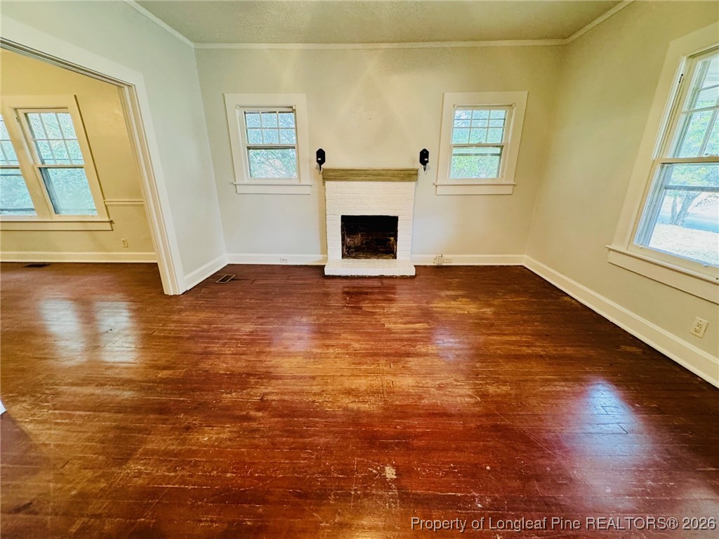 411 Carthage Road Lumberton, NC 28358 - Photo 6 of 25 an empty room with wooden floor and a fireplace