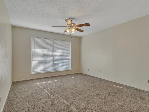 an empty room with windows and fan