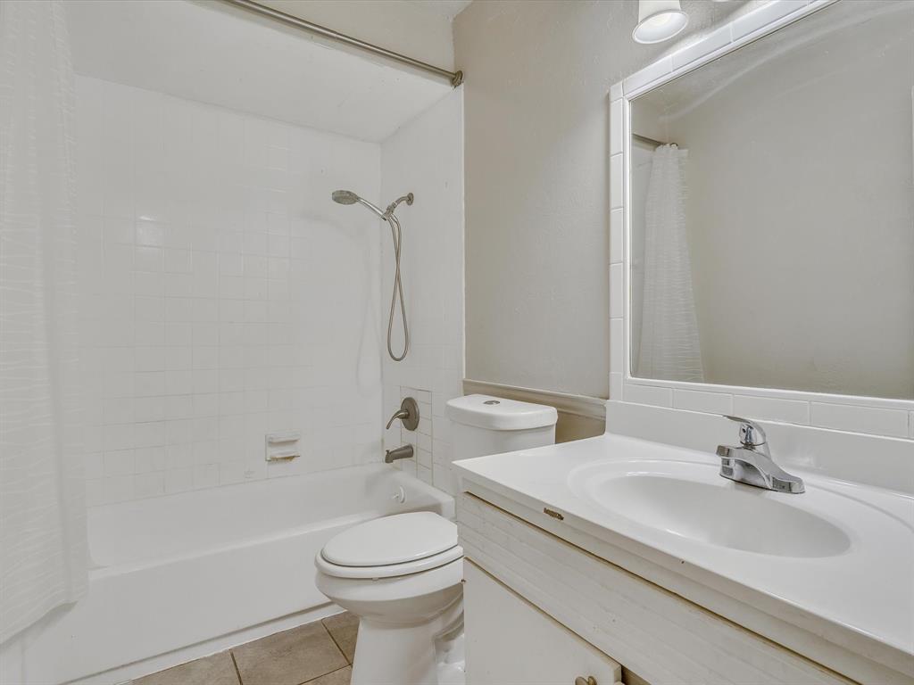 5053 Ridglea Lane, Unit 911 Fort Worth, TX 76116 - Photo 13 of 16 a bathroom with a granite countertop sink a toilet and a bathtub