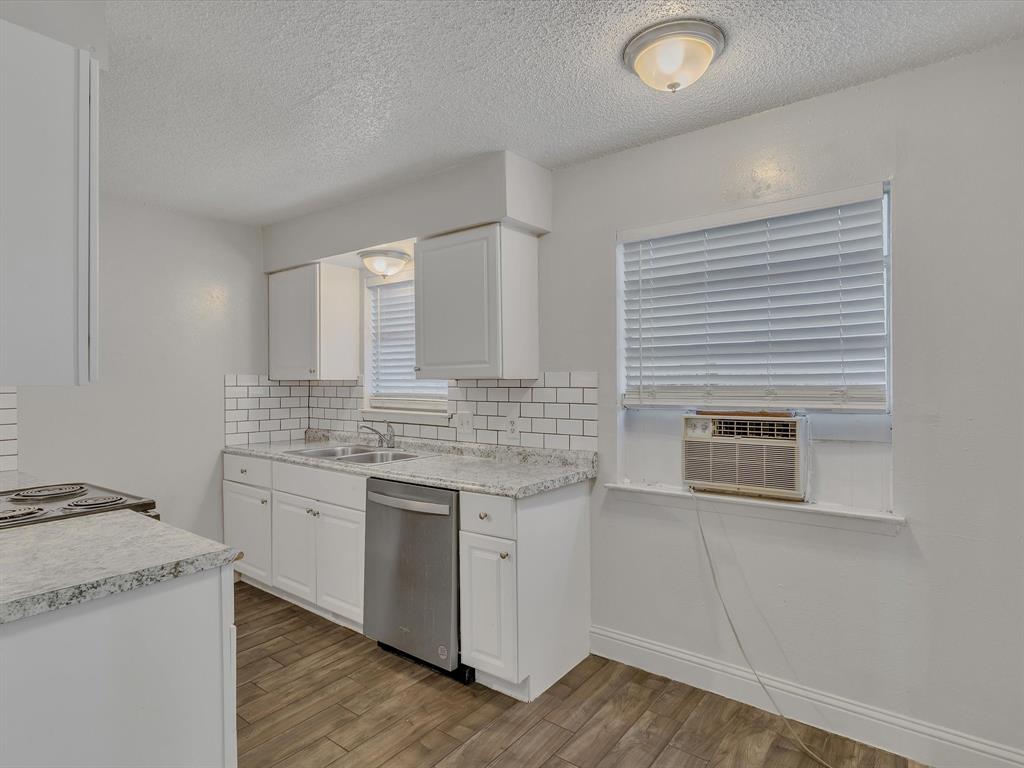 5053 Ridglea Lane, Unit 911 Fort Worth, TX 76116 - Photo 4 of 16 a kitchen with stainless steel appliances granite countertop a sink and dishwasher a stove top oven with wooden floor