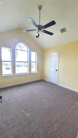 an empty room with windows and ceiling fan