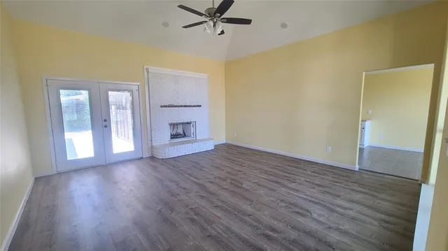 an empty room with wooden floor and a ceiling fan
