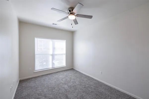an empty room with windows and ceiling fan