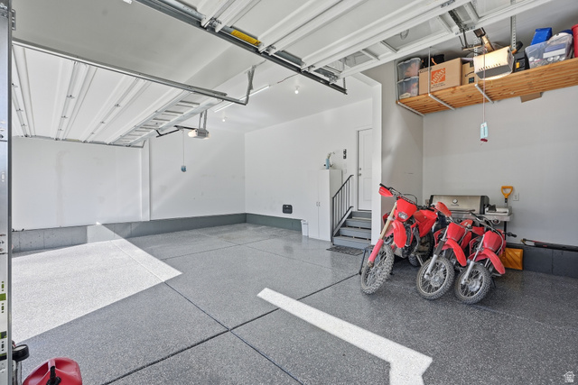 1202 South Raintree Lane Santaquin, UT 84655 - Photo 45 of 45 Spacious garage featuring a durable epoxy floor, overhead door, built-in shelving, and interior access stairs