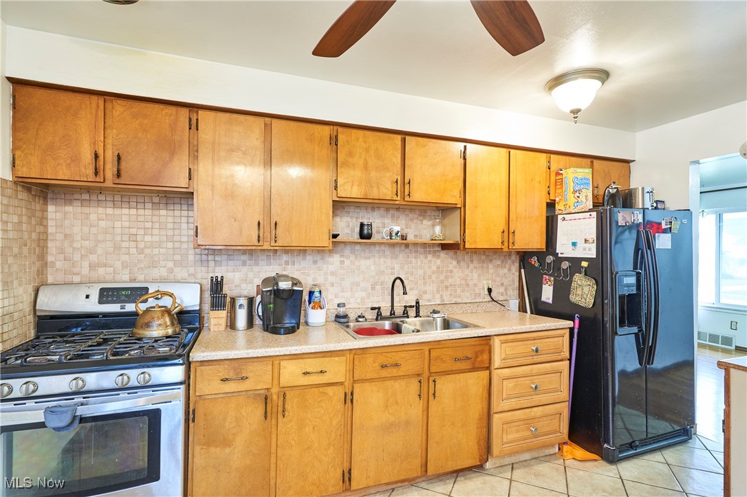 15813 Wingate Road Maple Heights, OH 44137 - Photo 7 of 26 Kitchen featuring light countertops, black refrigerator with ice dispenser, a sink, and stainless steel range with gas cooktop