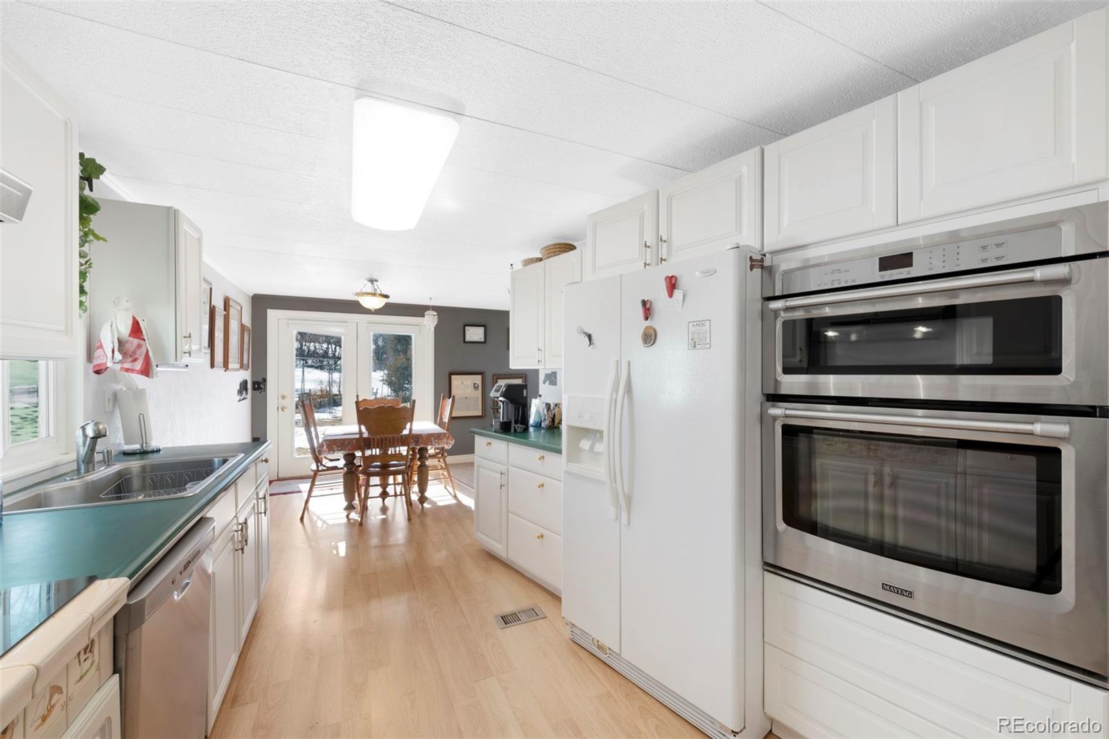 1382 Flintwood Road Franktown, CO 80116 - Photo 26 of 40 a kitchen with stainless steel appliances kitchen island granite countertop a stove a sink and a microwave