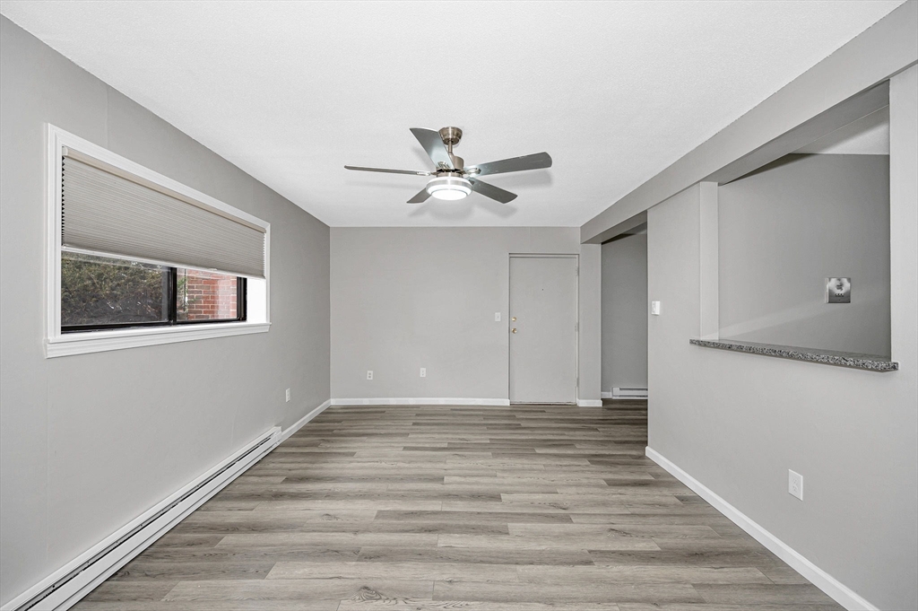 1241 Lawrence Street, Unit 101 Lowell, MA 01852 - Photo 12 of 27 a view of an empty room with wooden floor and a ceiling fan
