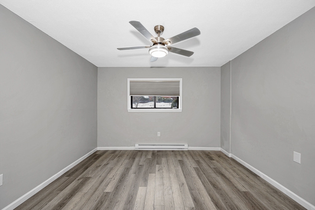 1241 Lawrence Street, Unit 101 Lowell, MA 01852 - Photo 15 of 27 an empty room with wooden floor and ceiling fan