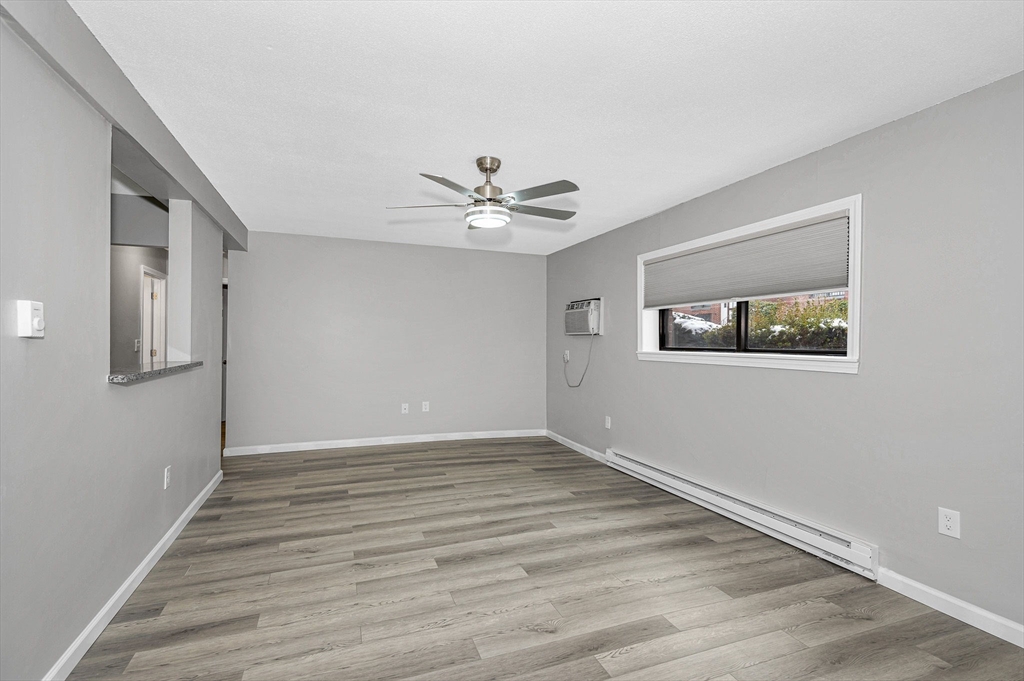 1241 Lawrence Street, Unit 101 Lowell, MA 01852 - Photo 8 of 27 a view of an empty room with wooden floor and a ceiling fan