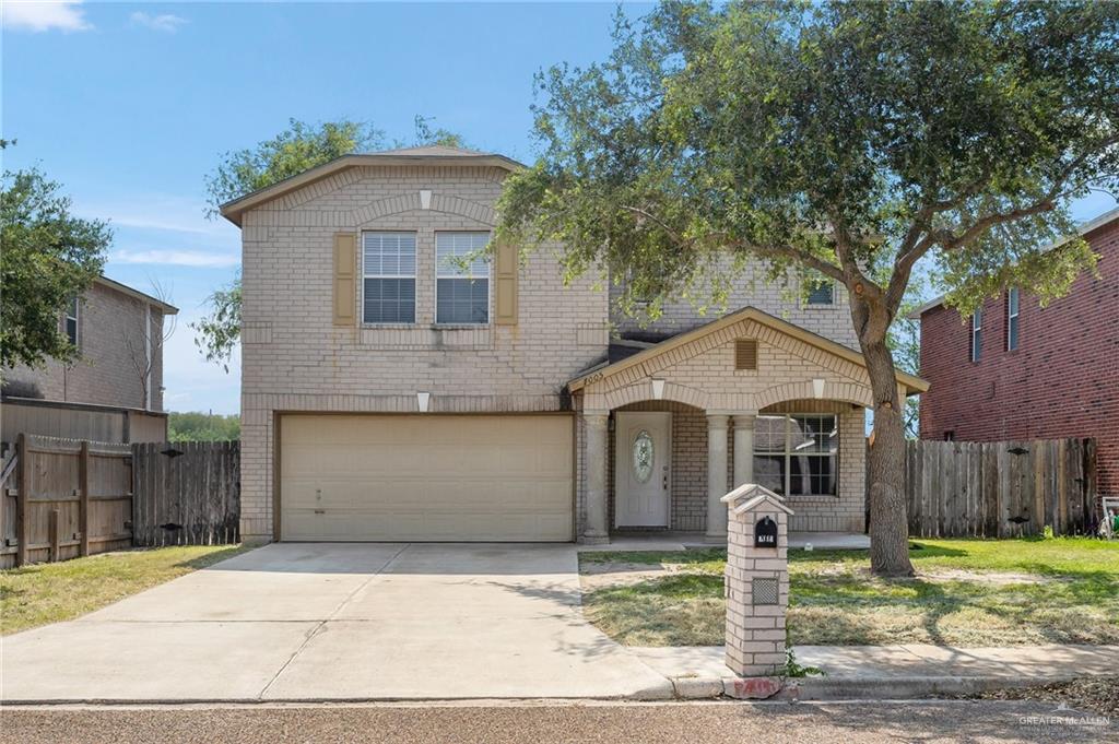 Traditional home featuring brick siding, driveway, an attached garage, and fence