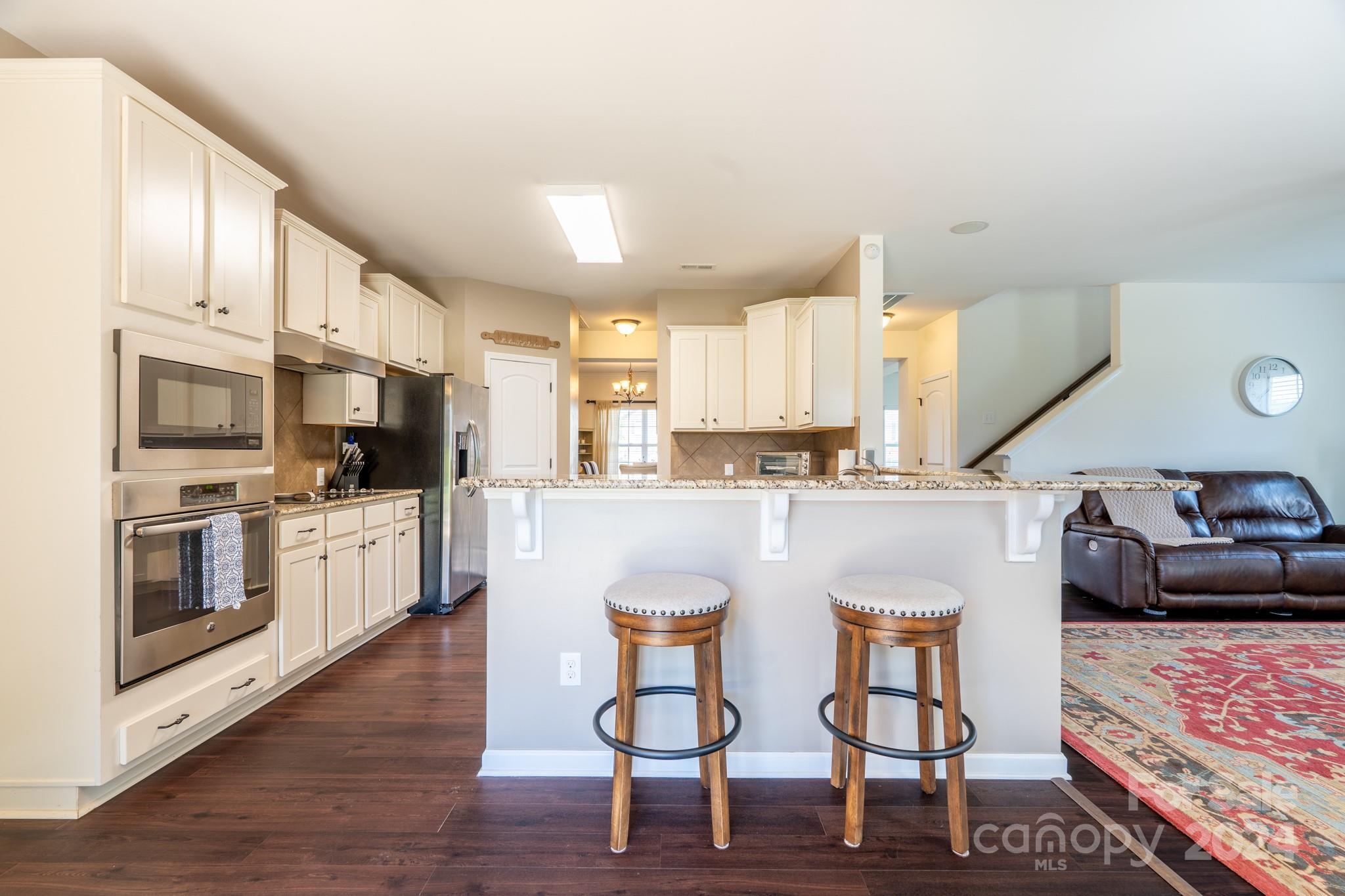 5396 Hackberry Lane Southwest Concord, NC 28027 - Photo 15 of 31 a kitchen with stainless steel appliances granite countertop a stove a sink dishwasher and a refrigerator with wooden floor