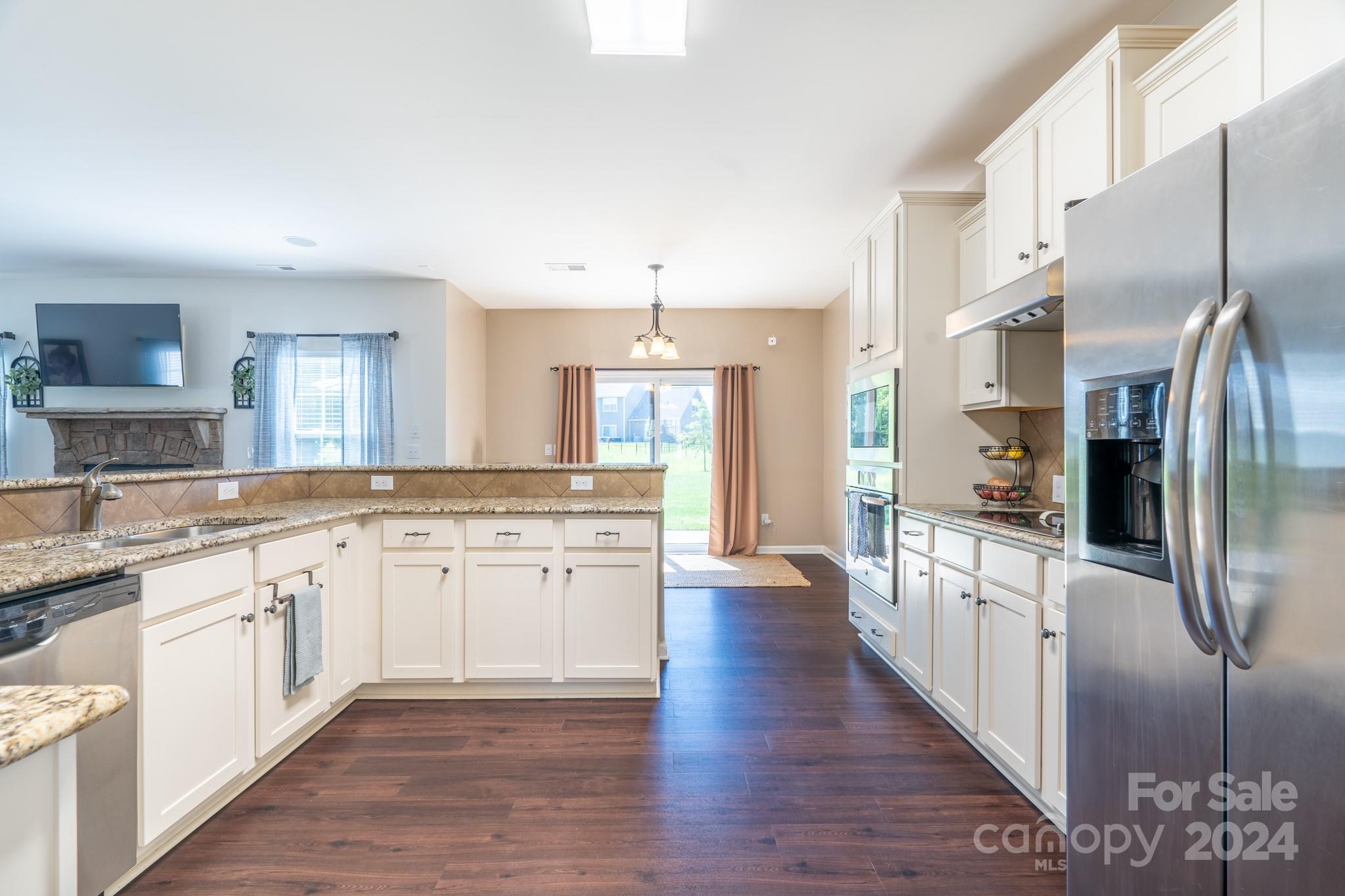 5396 Hackberry Lane Southwest Concord, NC 28027 - Photo 17 of 31 a large kitchen with stainless steel appliances kitchen island granite countertop a large refrigerator a oven and white cabinets with wooden floors