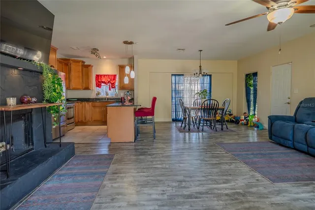 a kitchen with stainless steel appliances granite countertop a dining table chairs refrigerator and sink