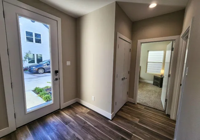 a view of a hallway with wooden floor and a bathroom