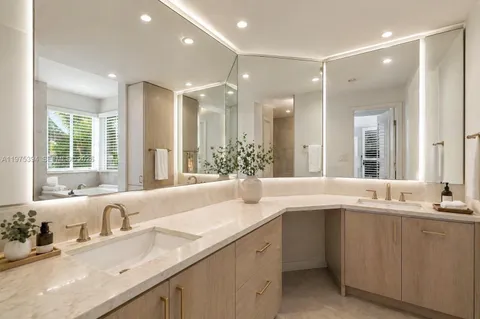 a bathroom with a double vanity sink large mirror and a bathtub