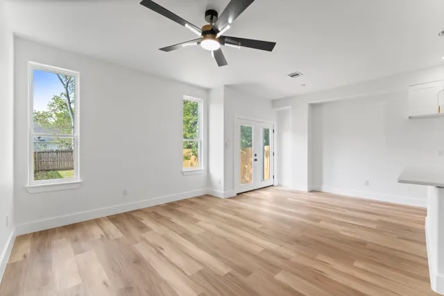 a view of an empty room with a window and wooden floor